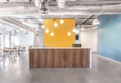 Reception desk with wood paneling and warm pendant lighting against a yellow backdrop.