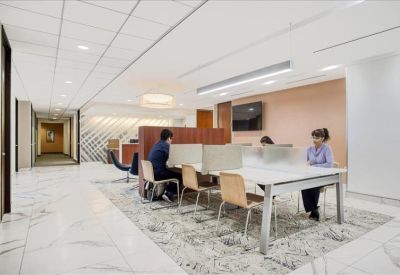 Spacious communal work area with several desks and warm salmon-colored feature walls.