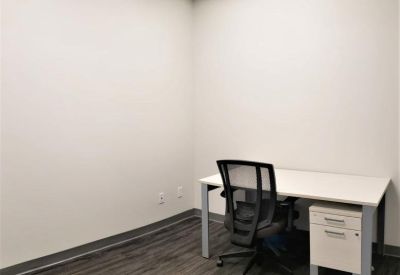 Private office featuring a white desk, grey mesh chair, and dark wood-style flooring.