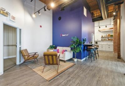 Communal lounge area with comfortable armchairs, a white sofa, and blue feature wall.