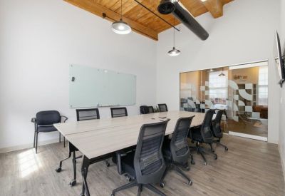 Spacious meeting room with a large light wood table and frosted glass wall.