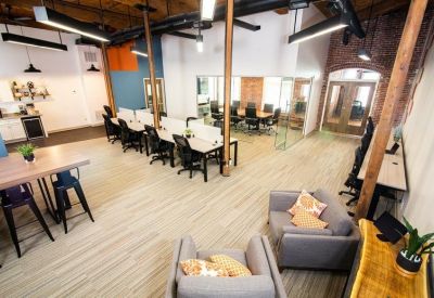 Spacious coworking area with lounge seating, high-top tables, and bright overhead lighting.