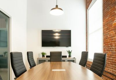 Modern conference room with a wooden table, leather chairs, and a large wall-mounted monitor.