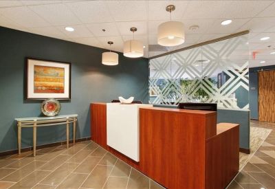 Modern reception area with a wood-fronted desk, teal accent wall, and decorative hanging lights.