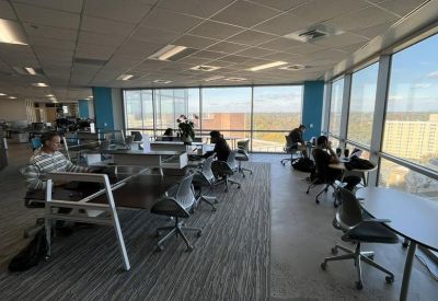 Sunlit coworking area with varied seating, blue accent pillars, and panoramic landscape views.