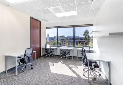 Bright office space with several desks situated along a wall of windows.