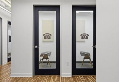 Modern hallway with two glass-door private phone booths and wood flooring.