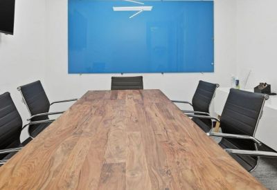 Meeting room with a long natural wood table and black ergonomic chairs.
