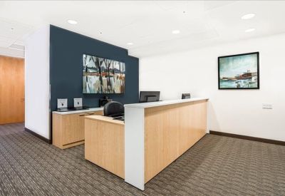 Professional reception desk with light wood paneling and a dark blue accent wall.