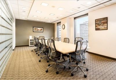 Bright boardroom with a long light-wood table and mesh ergonomic chairs.