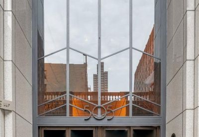 Grand entrance of 505 Montgomery Street with tall geometric glass windows and double doors.