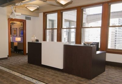 Professional reception area with a dark wood and white front desk by large windows.