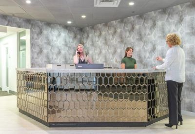 A modern reception desk with a hexagonal patterned metallic base and a textured feature wall.