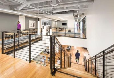 Multi-level open workspace with wooden floors and a modern black metal industrial staircase.