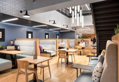 Modern breakout space with cafe-style tables, built-in booths, and a decorative pendant light fixture.