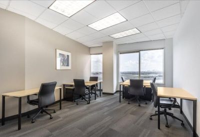 Spacious team office with four light wood desks and large windows.