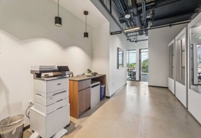 A row of modern printers and a mail station in a bright hallway.