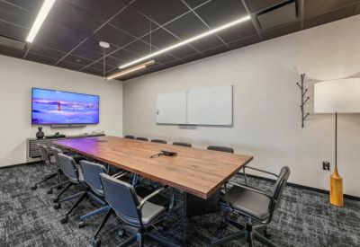Professional meeting room featuring a large wooden table and black ergonomic chairs.