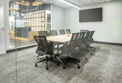 Long high-top meeting table with several chairs and vibrant abstract wall art.