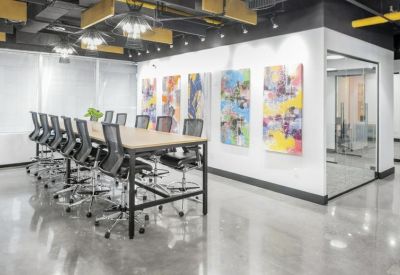 Spacious boardroom with a large conference table, high chairs, and vibrant abstract wall art.