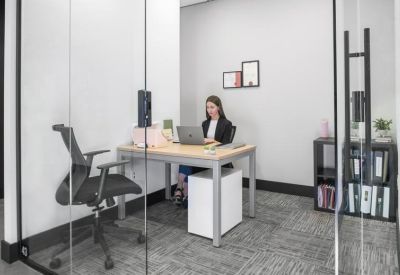 Private glass-walled office suite featuring a large desk and integrated shelving.