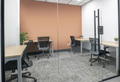 Shared three-person office suite with a warm orange accent wall and glass partition.