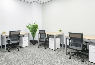 Bright internal workspace with three desks, mesh chairs, and white storage pedestals.