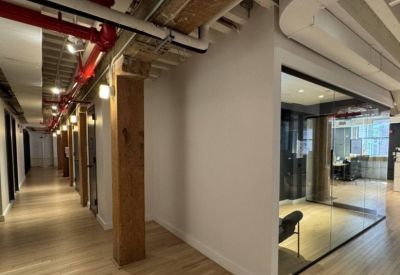 Clean white hallway with rustic wooden pillars and glass-walled private offices.
