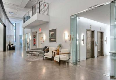 Bright reception area featuring grey armchairs and elevator access.
