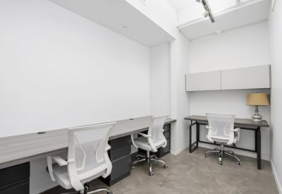 Private two-person office suite with white desks and overhead storage.