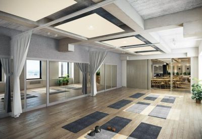 Bright wellness studio with yoga mats laid out on light wood floors and large wall mirrors.