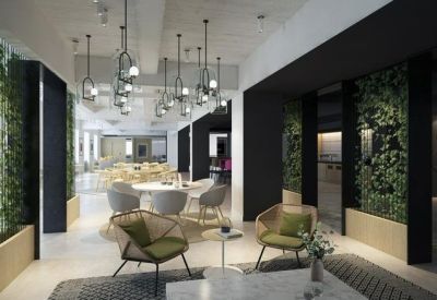 Modern lounge area featuring green accent chairs, marble tables, and lush vertical plant walls.