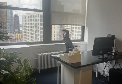 Private office suite featuring a black desk, ergonomic chair, and city views through large windows.