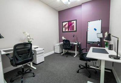 Private office with three white sit-stand desks and a purple accent wall.