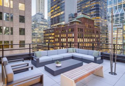 Spacious rooftop terrace lounge with modern sectional seating and city skyscraper views.