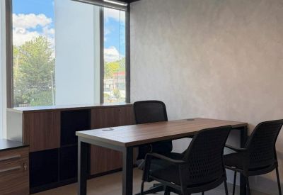 Private office featuring a wooden desk and black ergonomic chairs near a window.