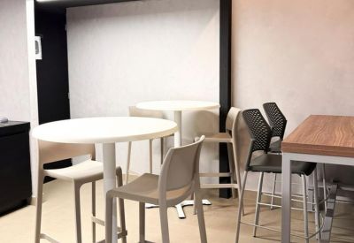 Breakout area with high white bistro tables and modern bar stools.