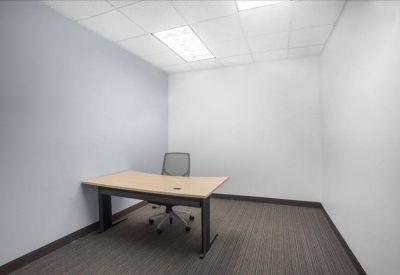 Private windowless office with a tan wooden desk and grey wall.