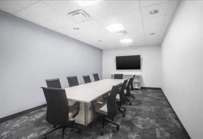 Spacious boardroom with a long white table and grey patterned carpet.