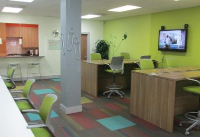 Bright coworking area with lime green walls and colorful carpet squares.