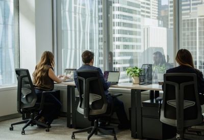 Bright open-plan workspace with desks and large windows overlooking city skyscrapers