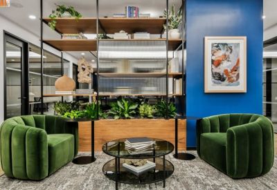 Stylish lounge area featuring green velvet chairs, a wooden planter, and a blue accent wall.