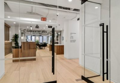 Office entrance with glass doors, a wood-paneled reception desk, and light wood flooring.