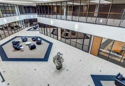 Spacious multi-story atrium lobby with central seating pods and glass-walled offices.