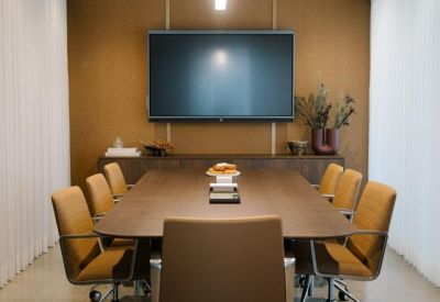 Modern boardroom featuring an oval table, leather chairs, and a large screen.