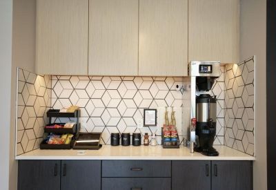 Modern kitchenette with a tile backsplash, coffee machine, and snack organizer.