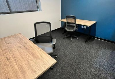 Small private office with two wooden desks and a blue accent wall.