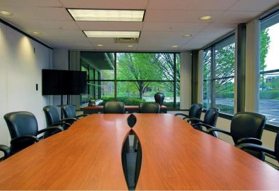 Spacious boardroom with a long wooden table and modern black chairs.