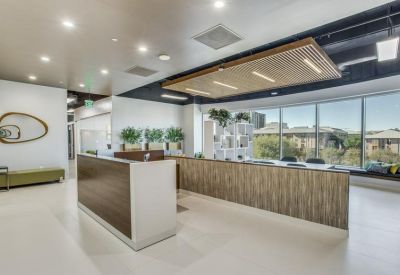 Bright modern reception area featuring a wood-paneled front desk and stylish light fixtures.
