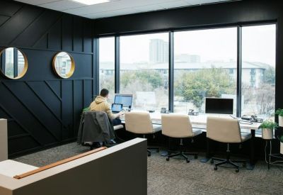 Sleek co-working space with a black feature wall, white desks, and large window views.